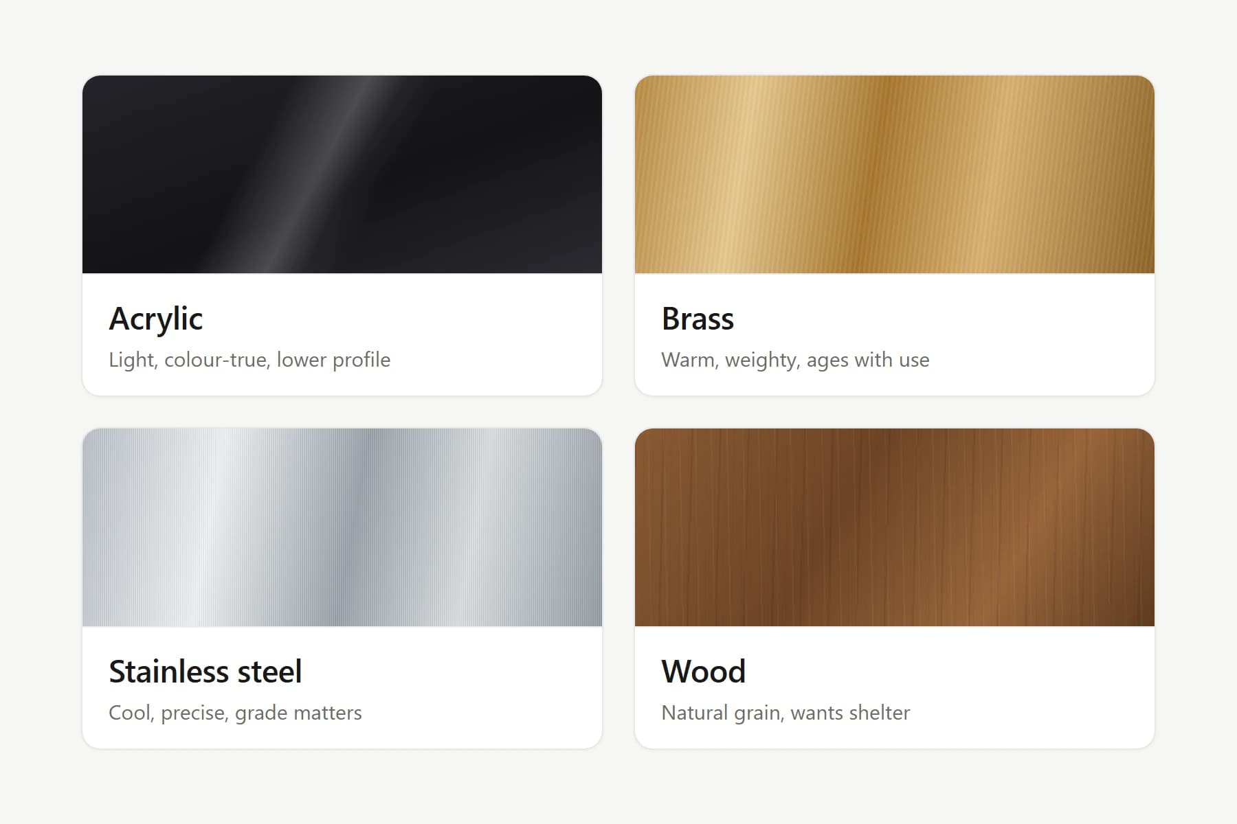 Four nameplate material swatches side by side: glossy black acrylic, warm brass, brushed stainless steel and grained wood